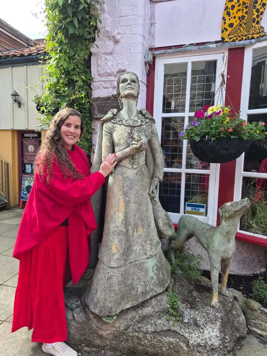 Hérica tocando a estátua de uma dama com seu cão