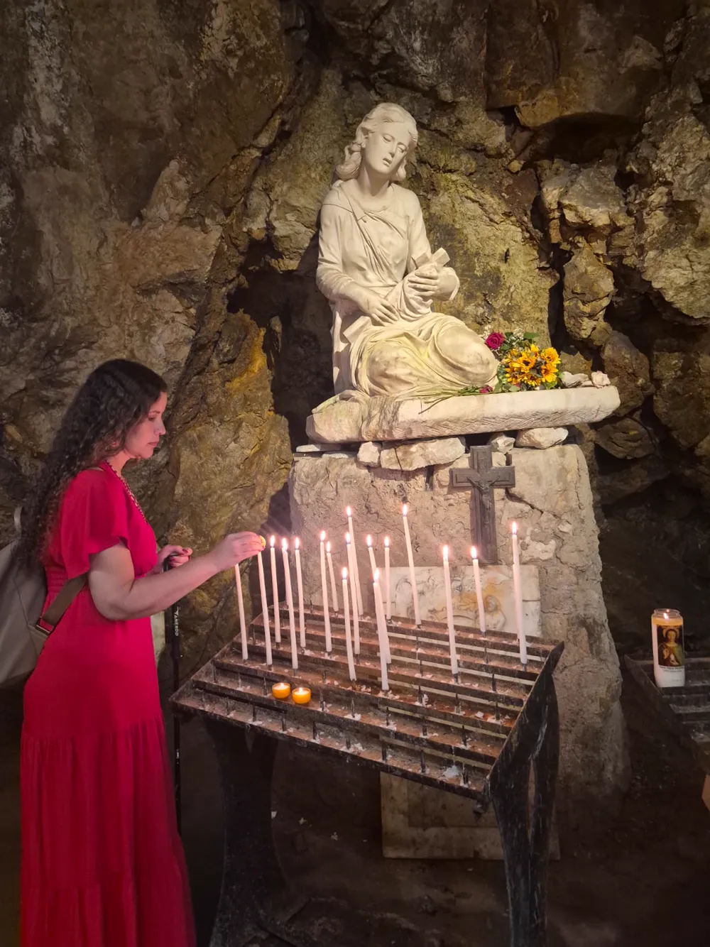 Hérica acendendo uma vela diante da imagem de Maria Madalena