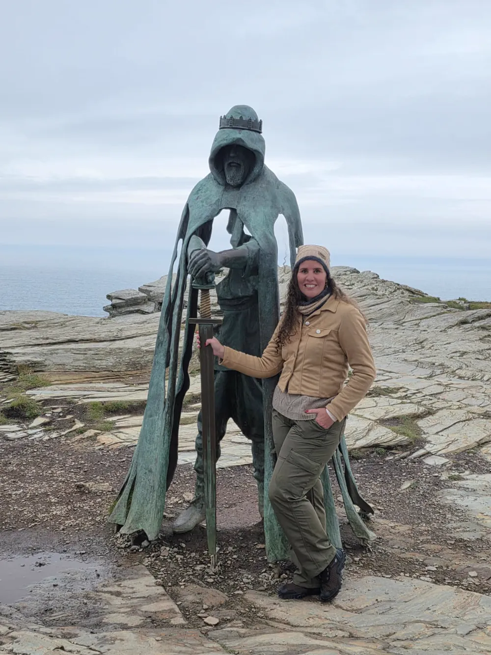 Hérica ao lado da estátua do rei com a espada, sobre o mar
